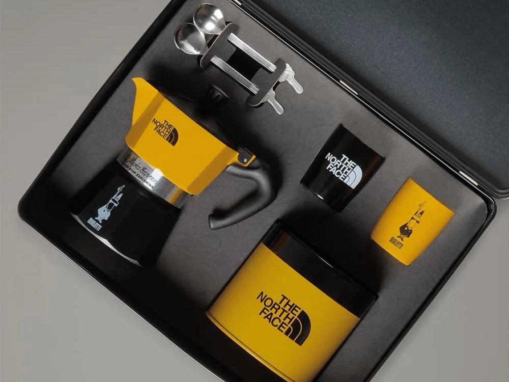 Krabička s moka konvičkou, šálky a lžičkami ve žluté barvě a spolupráci s firmou The North Face.